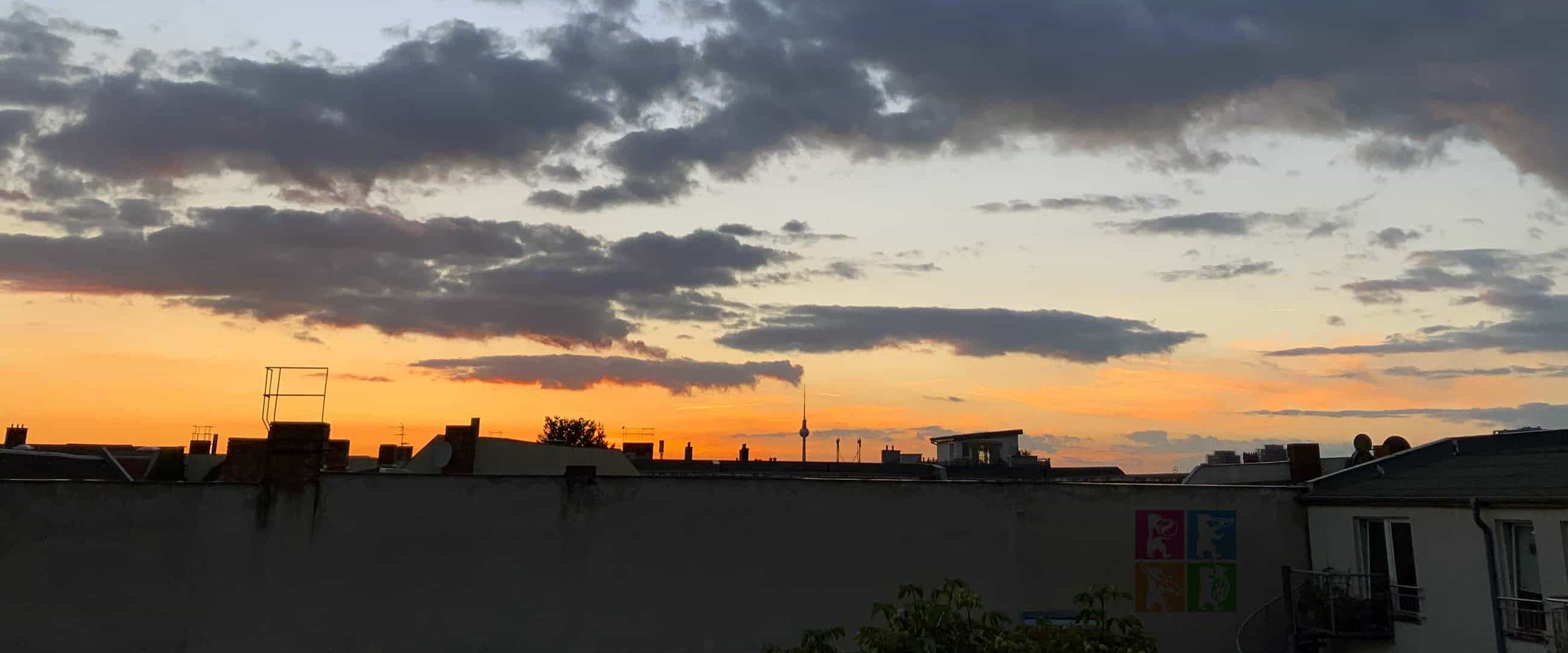 Panorama von Berlin bei Abenddämmerung. Im Vordergrund ist eine Hauswand mit dem Logo des Bläsertreffens